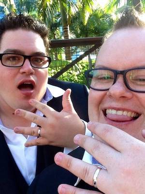 A photo of the two of us showing off our wedding rings